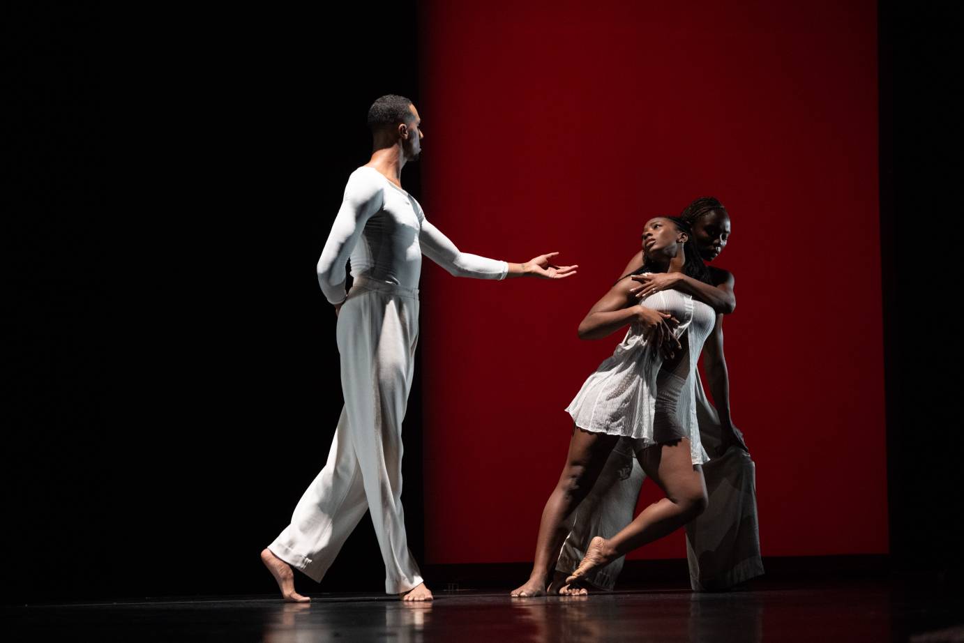 a tall male figure in white reaches angellically toward a couple in white who seem stricken and longing 