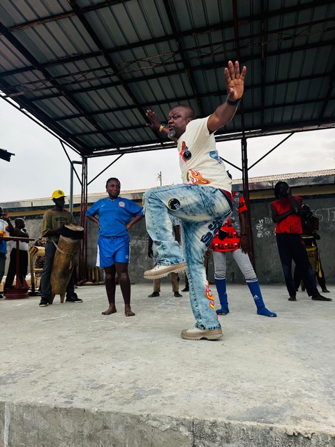 Andoche Loubaki in jeans and t shirt showing his colleagues a balancing movement on the rehearsal stage