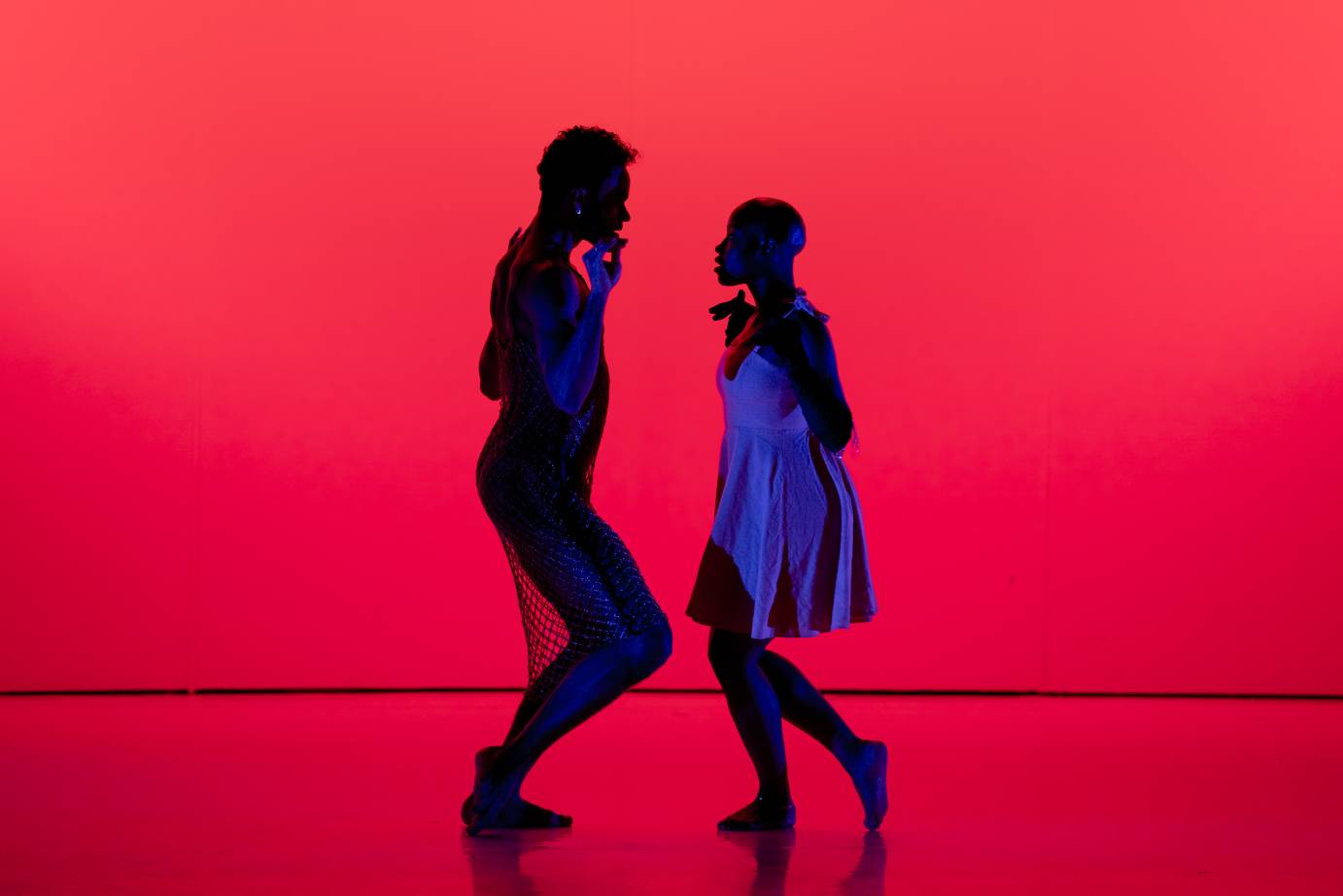 a red background with two silouetted dancers facing one another 