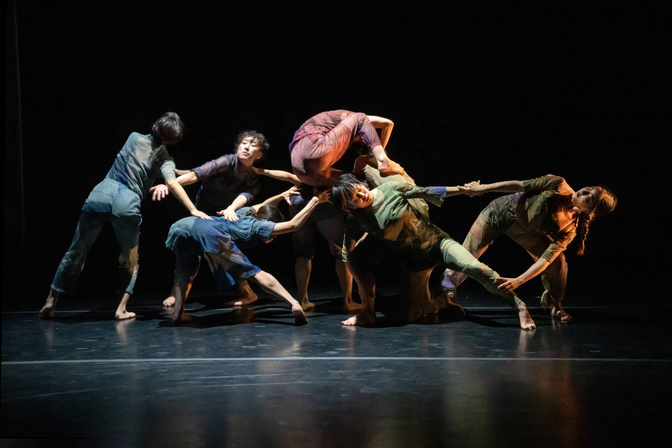 A company of eight women form a platform for two layers of dancers to climb on top of one another.