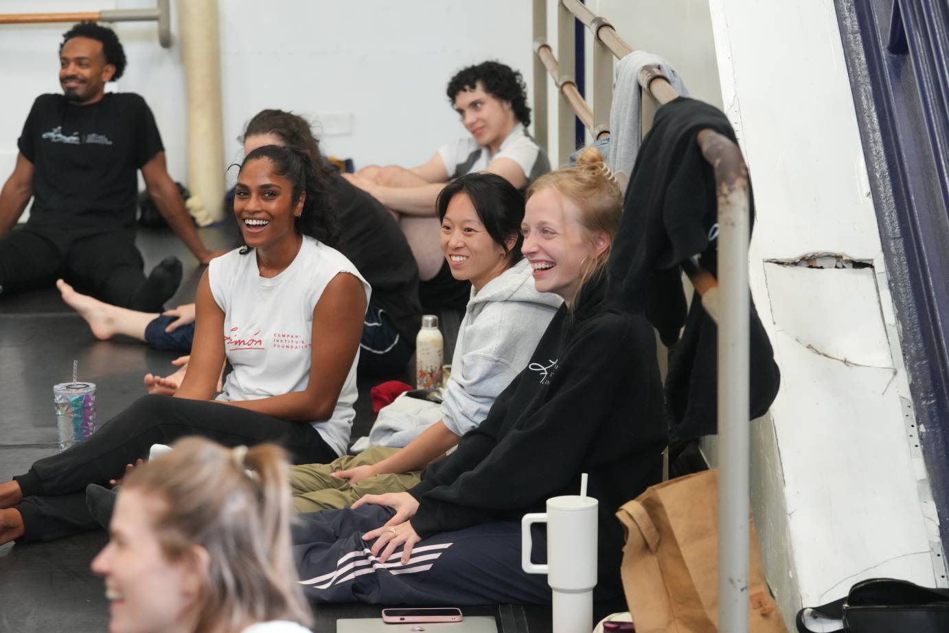 dancers on break sit on the floor and laugh 