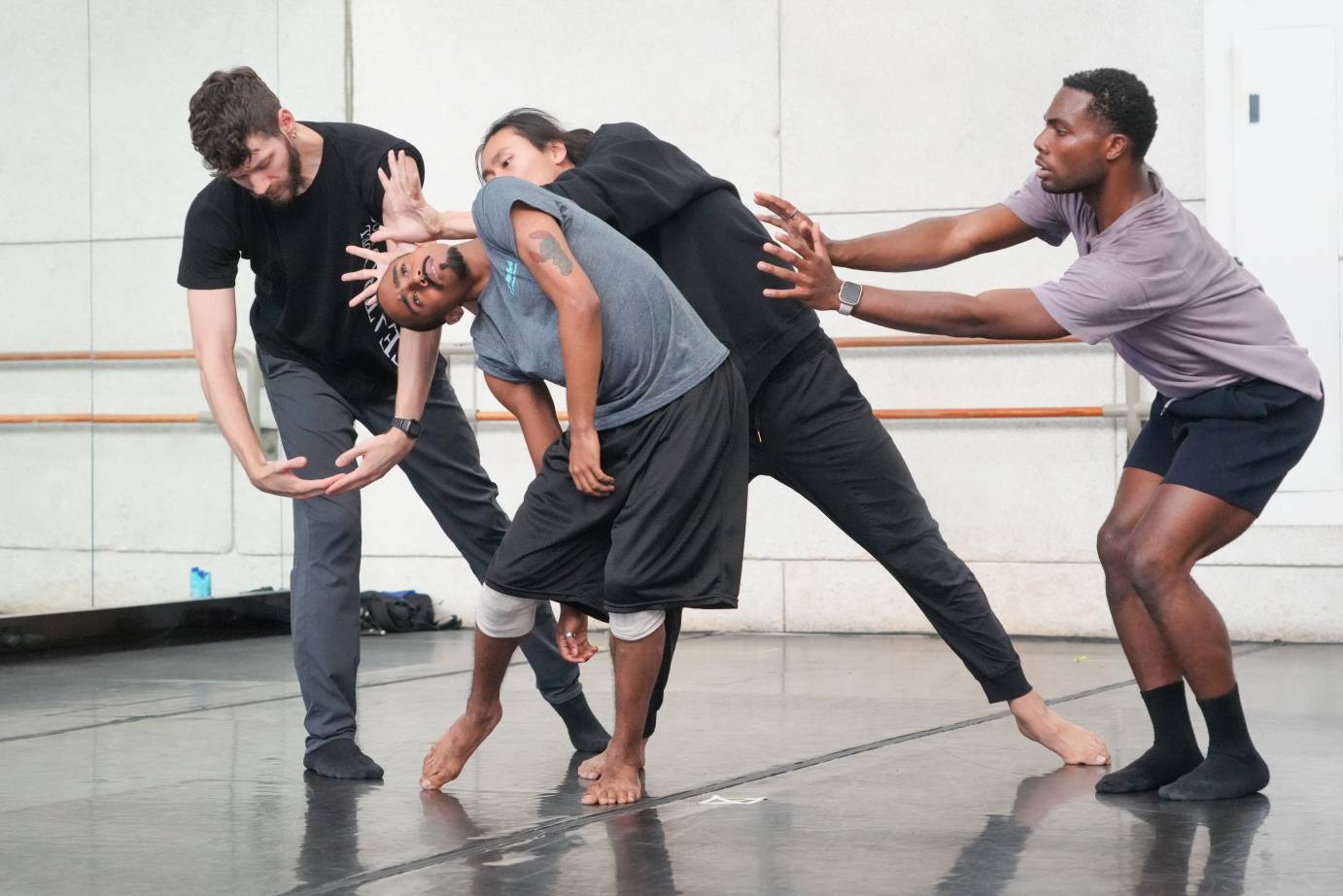 the dancers in sweats pose in mid action as MJ Jackson leans to one side Johnson Guo seems to be creating a crown of thorns around MJ's head 