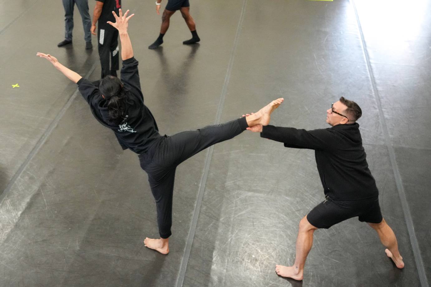 the artistic director Dante Pulieo holds on to Johnson Gou's high side leg extension as Johnson leans  his body away from his high leg