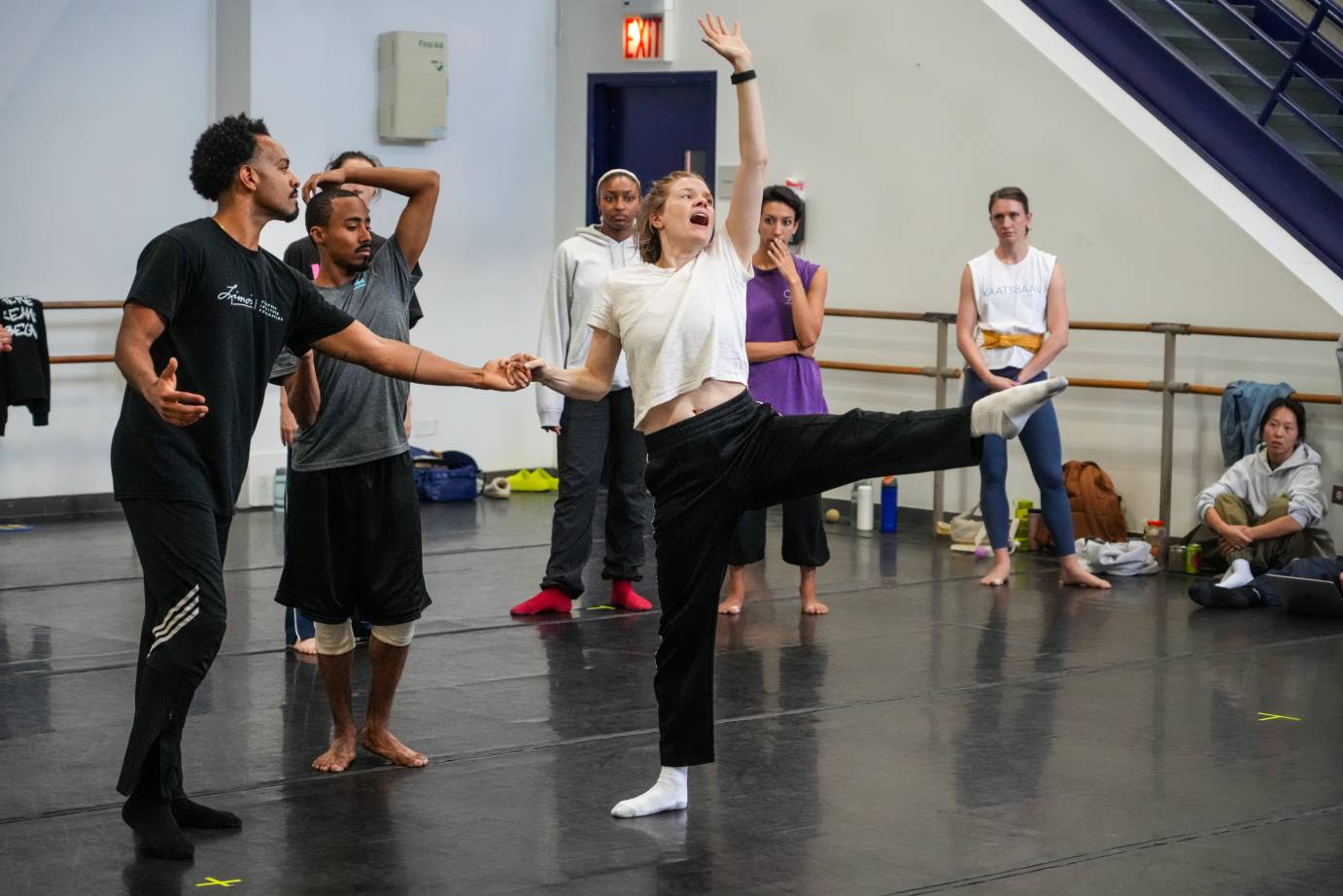 the rehearsal director jumps into the dance and demonstrates the energy needed for a side kick in the work