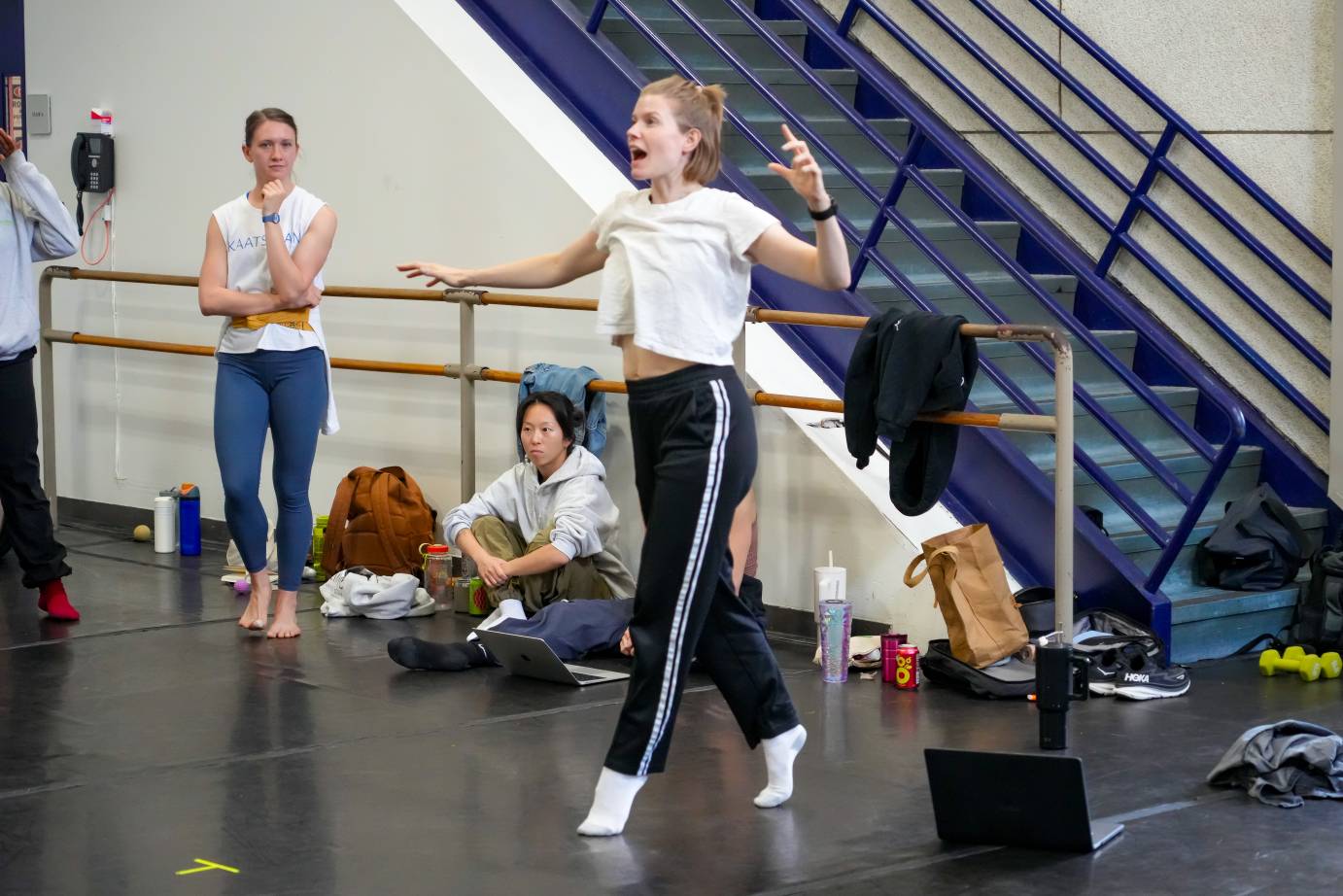 the rehearsal director energetically stands on her toes giving excited notes