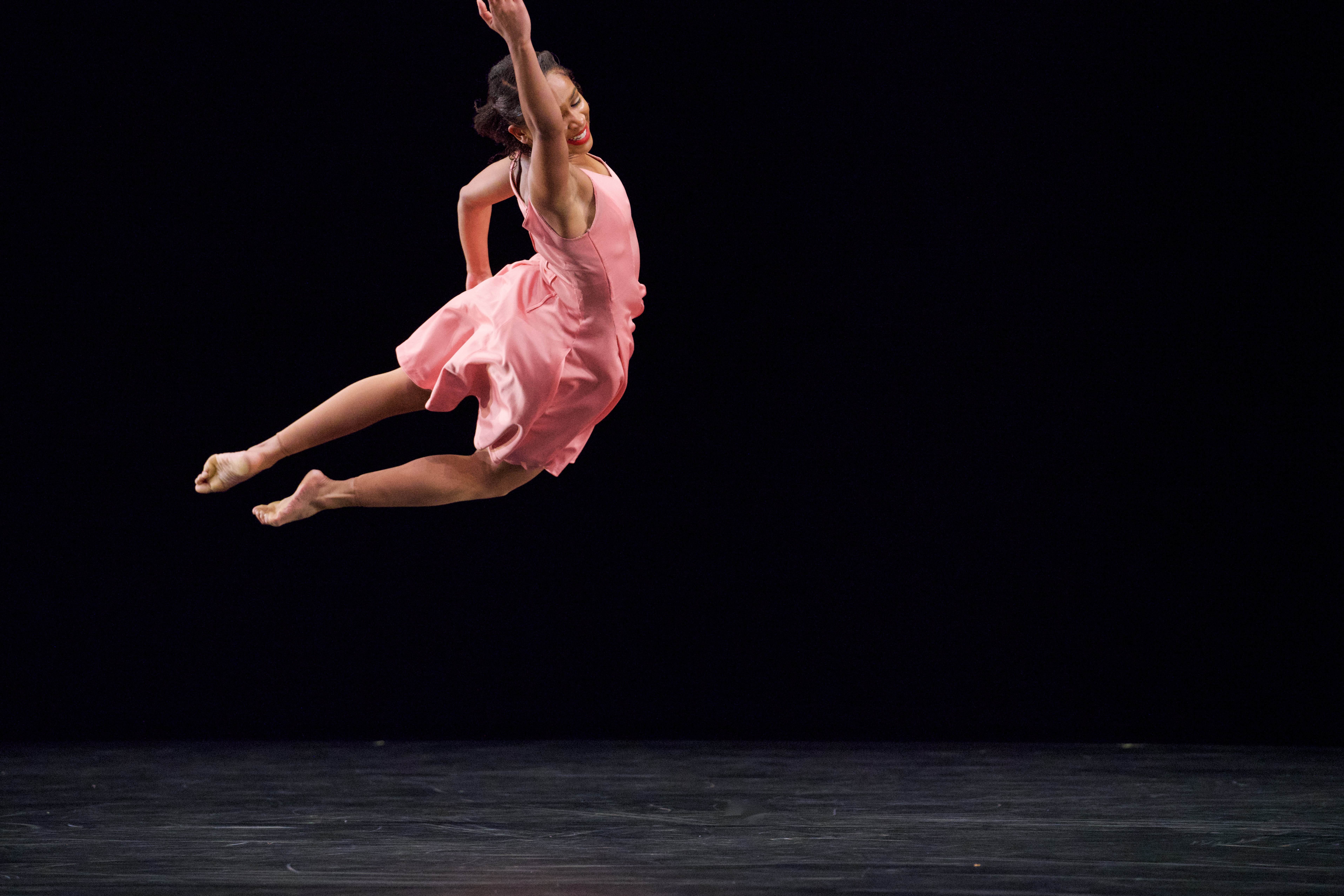 woman in pink dress in the midst of a jubilant jump