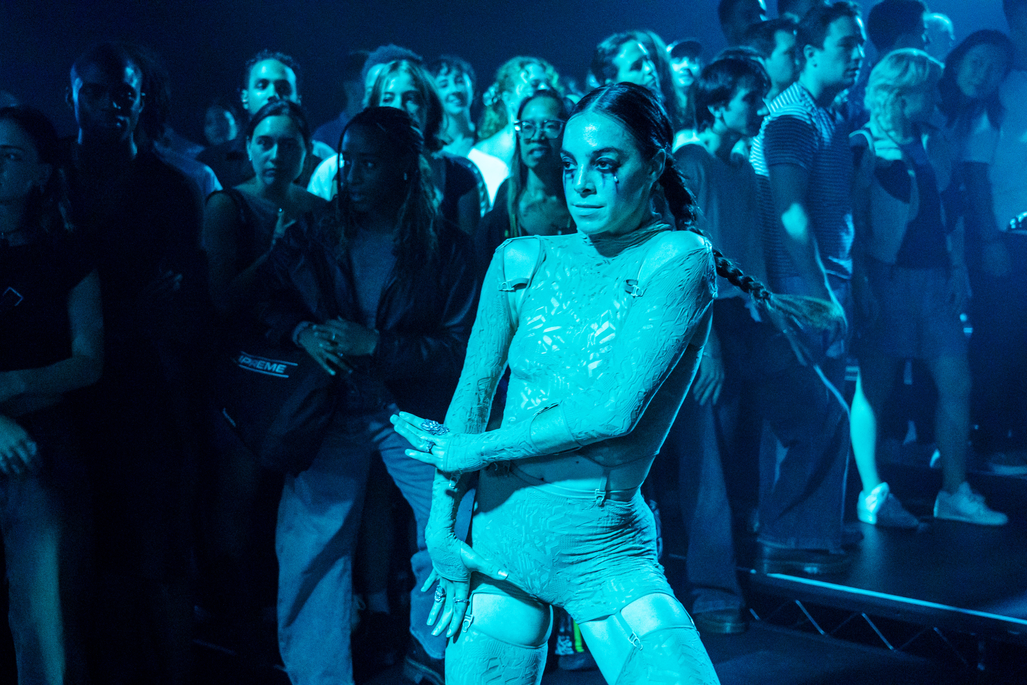 in blue light dancer in lace with makeup running down her eyes freezes in the middle of a dance as spectators look on