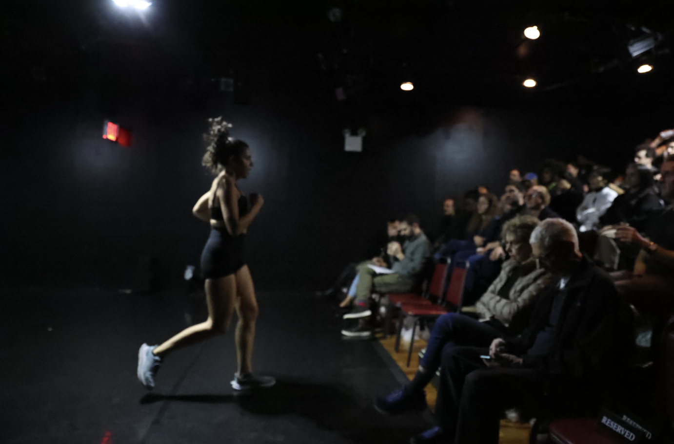 another view of the girl in jugging shorts, sports bra, speaking or singing to the audience 