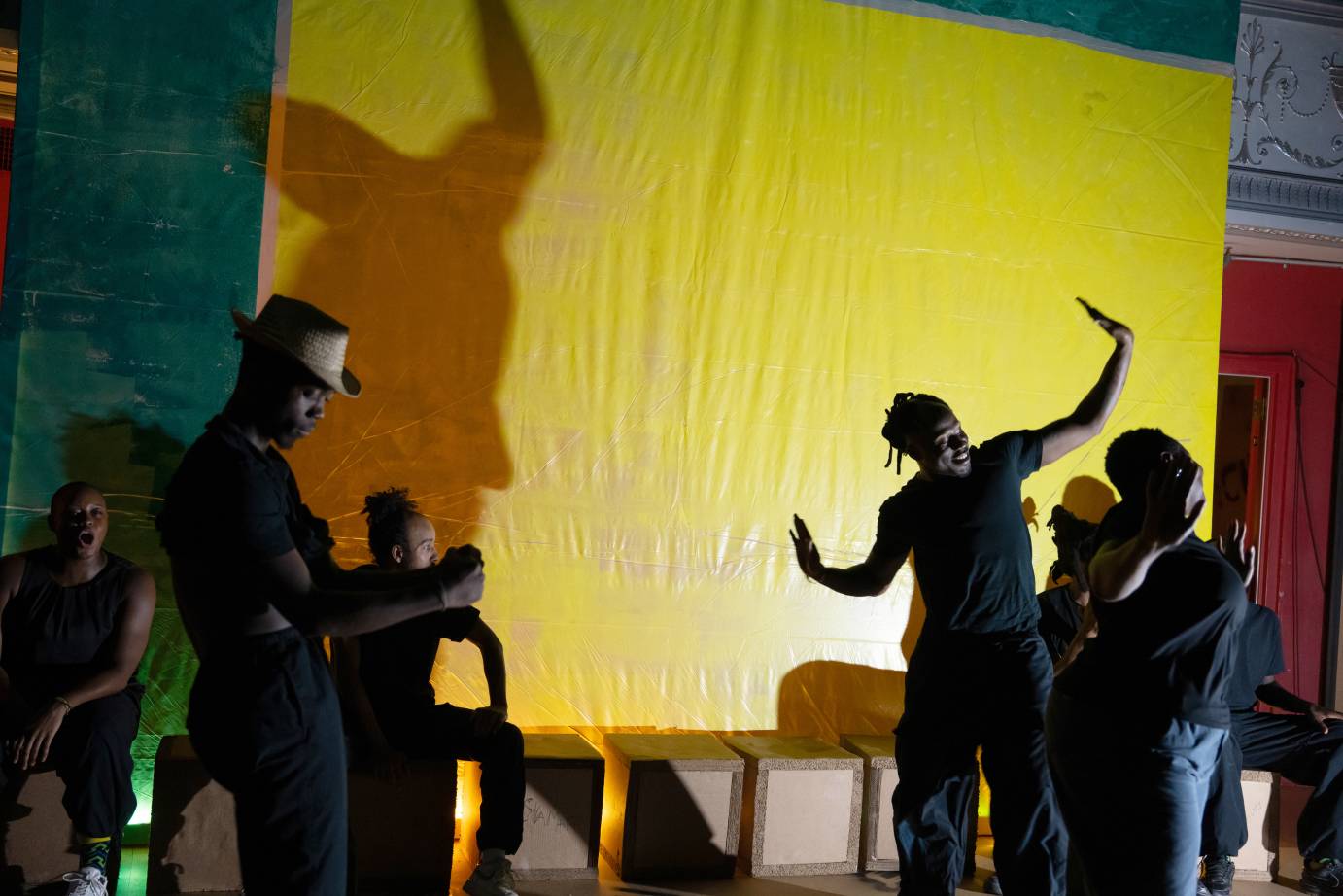 bodies and their shadows against a yellow screen
